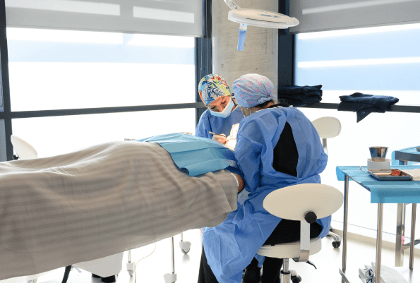 eine Frau im Operationssaal mit den Ärzten, die eine Haartransplantation Berlin
