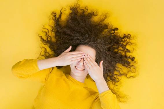 Frau bedeckt ihr Gesicht und zeigt ihre Locken haartransplantation verbergen