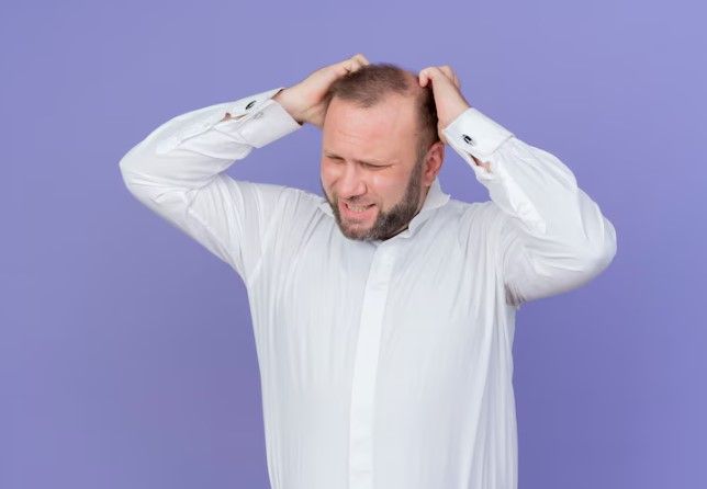 Mann hält seinen Kopf und leidet unter den emotionalen Folgen von Alopezie - psychologischen konsequenzen alopezie haartransplantation